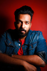 Portrait of young man sitting against yellow background