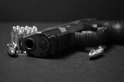 Close-up of handgun with bullets on table