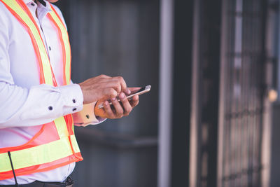 Midsection of engineer using mobile phone