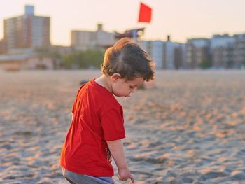 Cute little boy exploring an empty beach at sunset