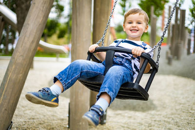 Portrait of happy boy on swing at playground