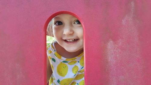 Portrait of a smiling girl standing against pink wall