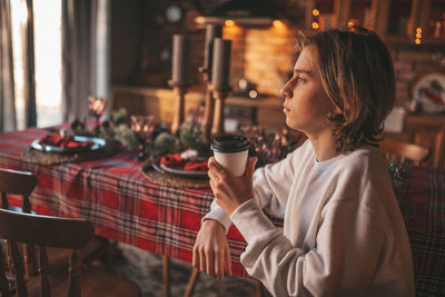 Portrait of candid authentic smiling handsome boy teenager using mobile phone at xmas home interior