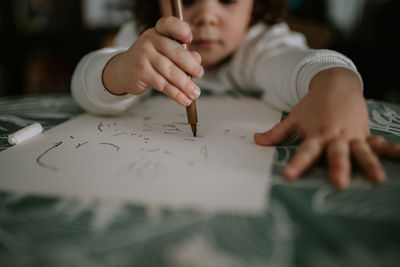 Midsection of girl drawing on paper at home