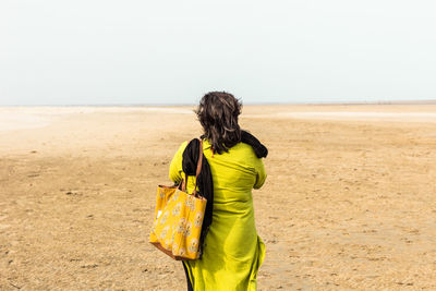 Rear view of woman on beach against clear sky