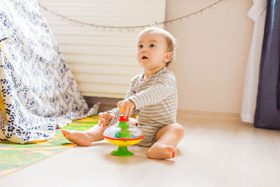 Cute boy sitting on toy at home