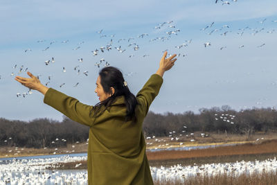 Low angle view of woman with birds flying over water