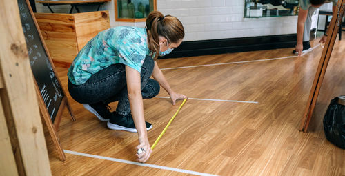 Side view of woman sitting on hardwood floor at cafe