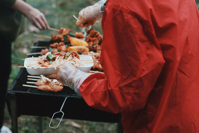 Midsection of person roasting food on barbecue grill