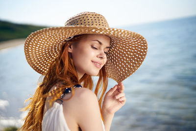 Portrait of young woman wearing hat against sky