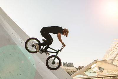 Man riding bicycle on built structure against sky