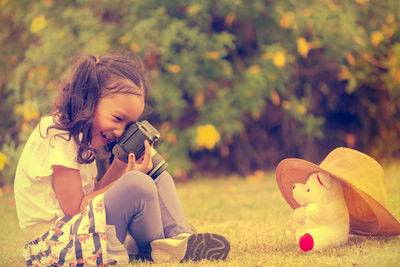 Woman photographing while sitting on field