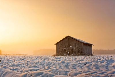 Built structure on snow against sky at sunset