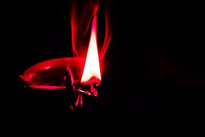 Close-up of lit candle against black background