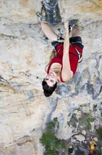 Directly above portrait of smiling young woman climbing rocky mountain