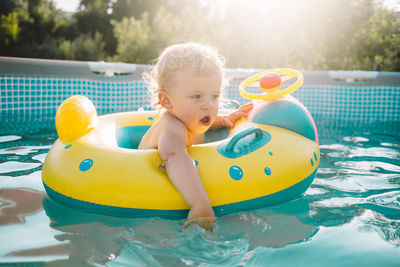 Baby boy sitting in inflatable ring on swimming pool