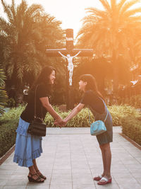 Full length of mother and daughter against trees