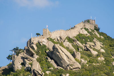 Low angle view of castle on mountain against blue sky