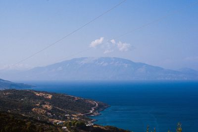 Scenic view of sea and mountains against blue sky