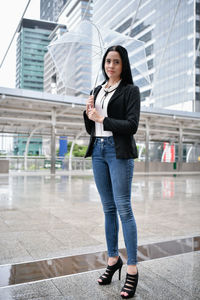 Portrait of businesswoman with umbrella standing on street