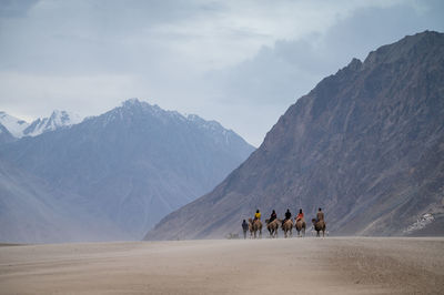 People walking on desert against sky