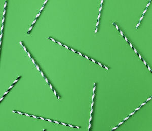 Full frame shot of straws arranged on green background