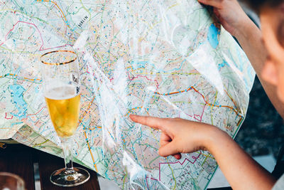 Close-up high angle view of woman pointing at map by drink