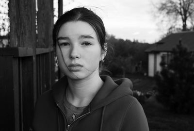 Close-up portrait of young woman against house