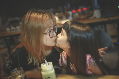 Mother kissing daughter while sitting at cafe