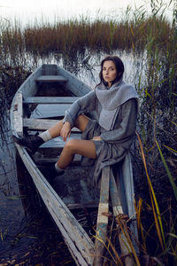 Woman sitting in a gray sweater and skirt next to the lake in the fall