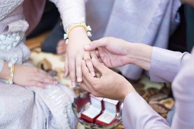 Close-up of man putting ring on bride