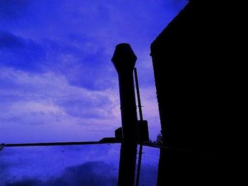 Low angle view of silhouette cross against blue sky