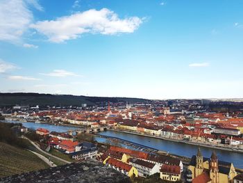 High angle view of illuminated city by river against sky