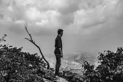 Man standing on rock against sky