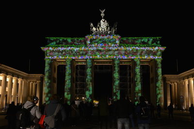 Group of people in front of illuminated building at night