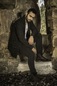 Portrait of young handsome man sitting on rock formation