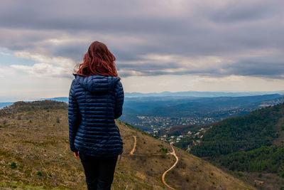 Rear view of woman standing on mountain against sky
