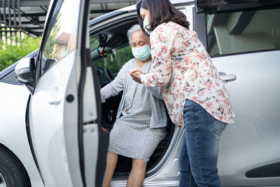 Side view of young woman standing in car