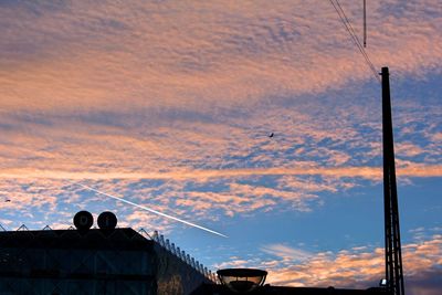Silhouette airplane flying against sky during sunset