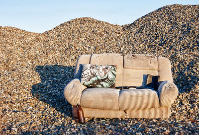 Chairs on rocks on beach against sky