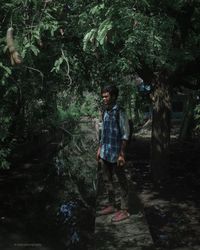 Girl standing by tree in forest