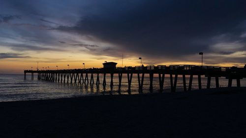Silhouette pier on beach against sky during sunset