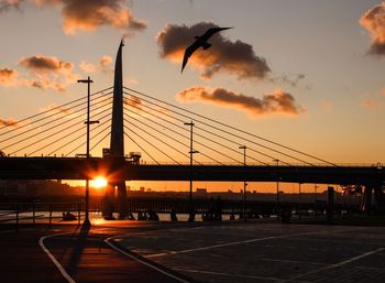 Silhouette bridge against sky during sunset in city