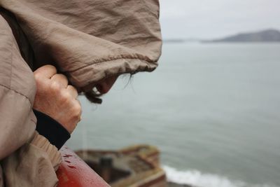 Close-up of man hand on beach against sky