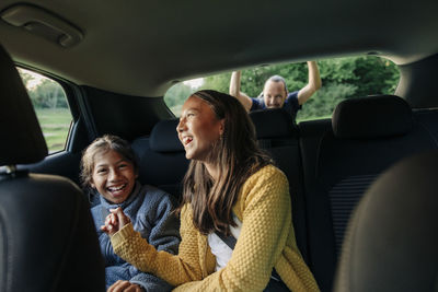 Cheerful sisters laughing while sitting in car