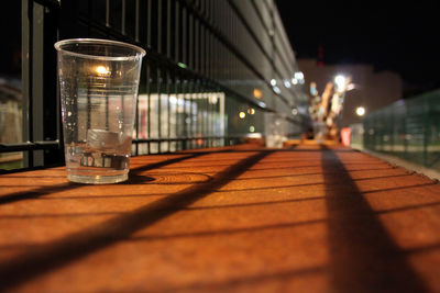 Close-up of disposable glass by fence at night