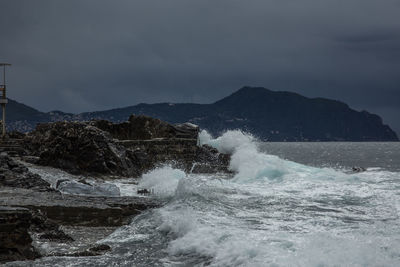 Waves splashing on rocks against sky