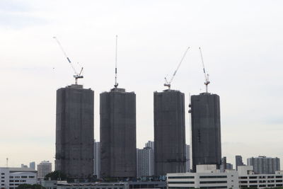 Cranes at construction site against sky in city