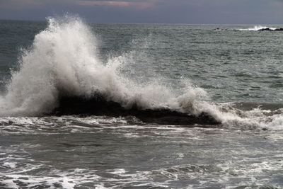 Waves splashing on sea against sky