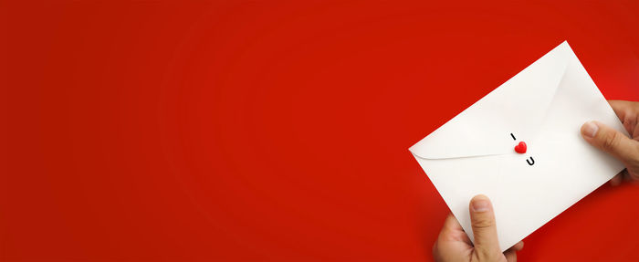 Person holding paper against red background